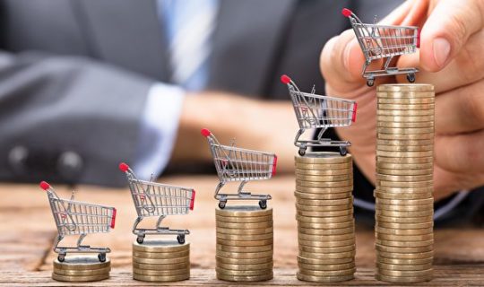 Midsection,of,businessman,placing,shopping,cart,on,stacked,coins,in
