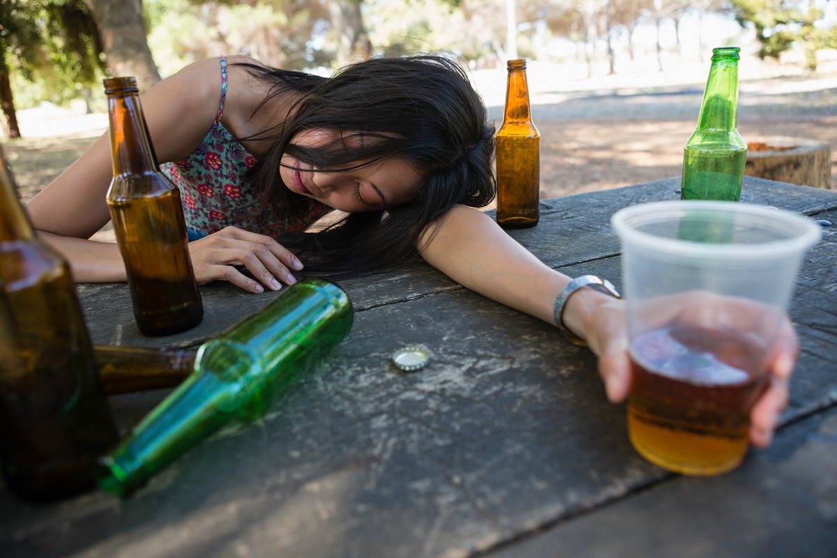 Drunken Woman Relaxing On The Table Holding A Glass