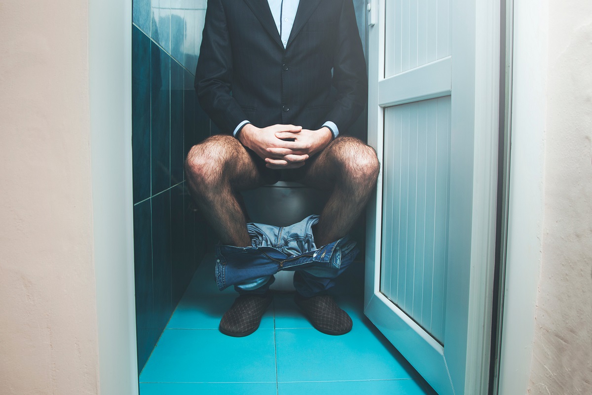 Man Sitting On A Toilet Seat With His Pants And Boxers Down