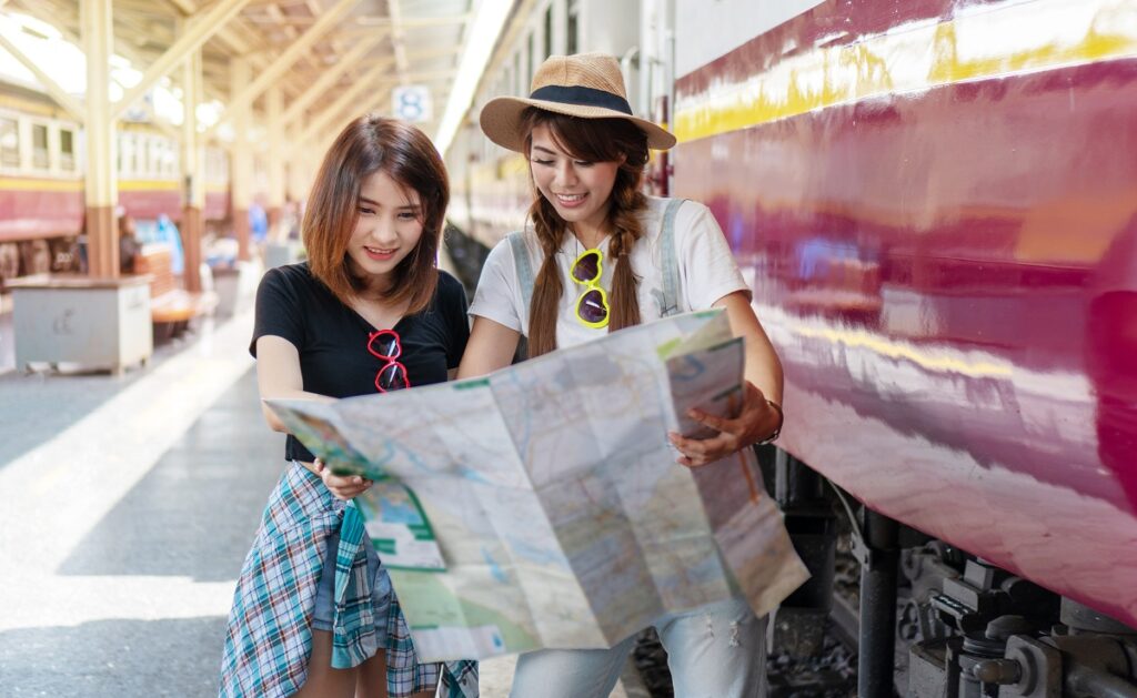 Happy travel together of two young woman looking map in train st