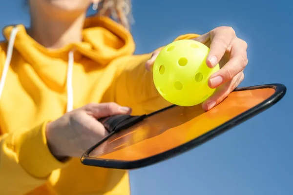 Pickleball Paddle And Yellow Ball Close Up, Woman Playing Pickleball Game, Hitting Pickleball Yellow Ball With Paddle, Outdoor Sport Leisure Activity.