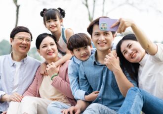 Image Of An Asian Family Sitting Together On The Grass At The Park