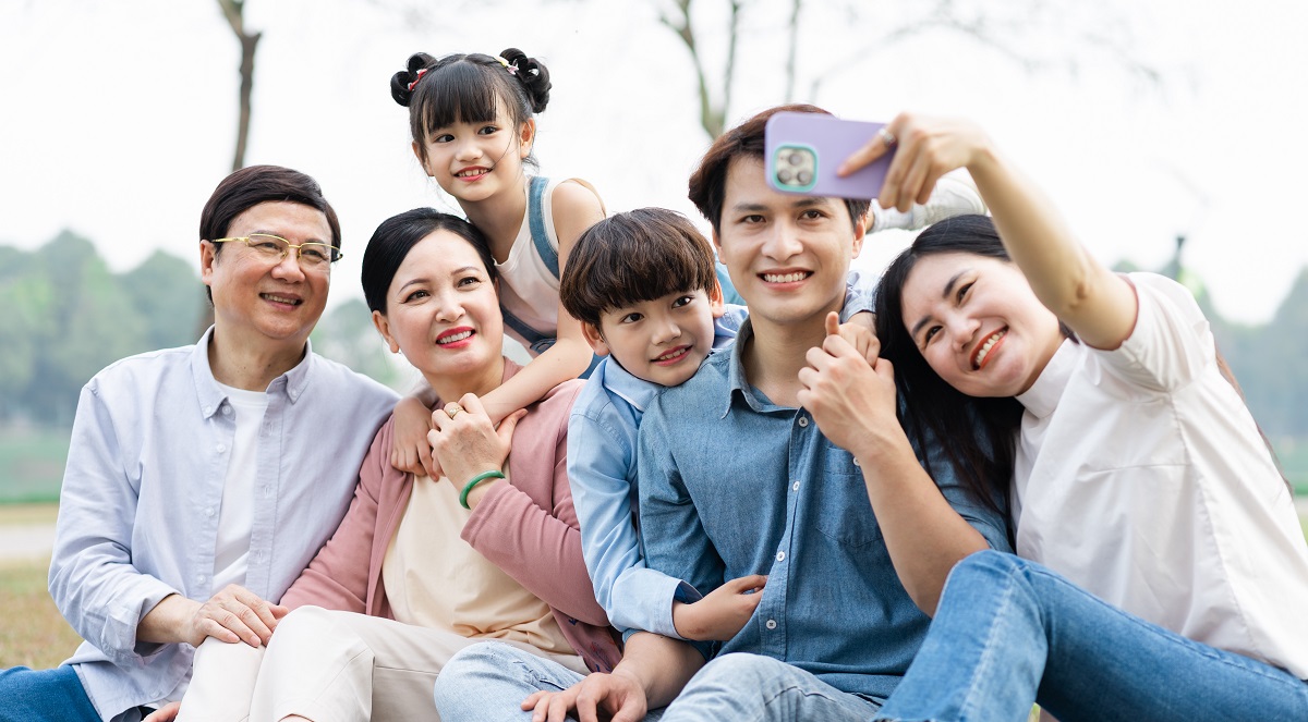Image Of An Asian Family Sitting Together On The Grass At The Park